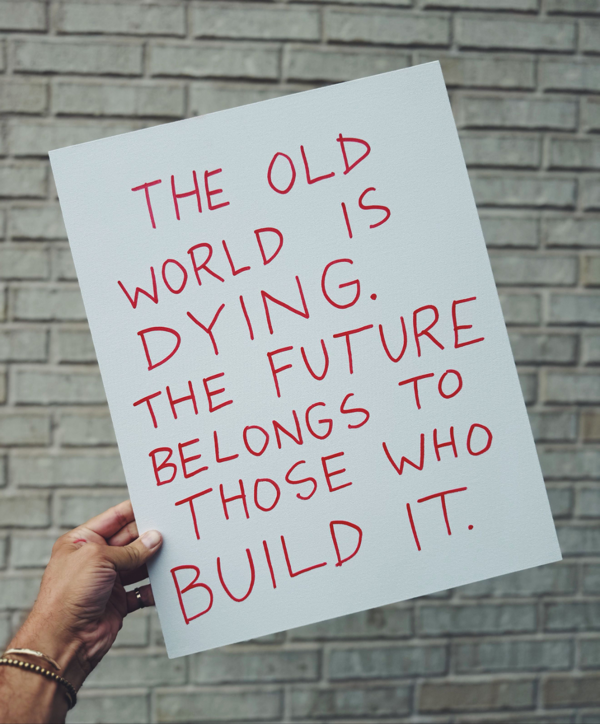 James McCrae holding a sign: The old world is dying. The future belongs to those who build it.
